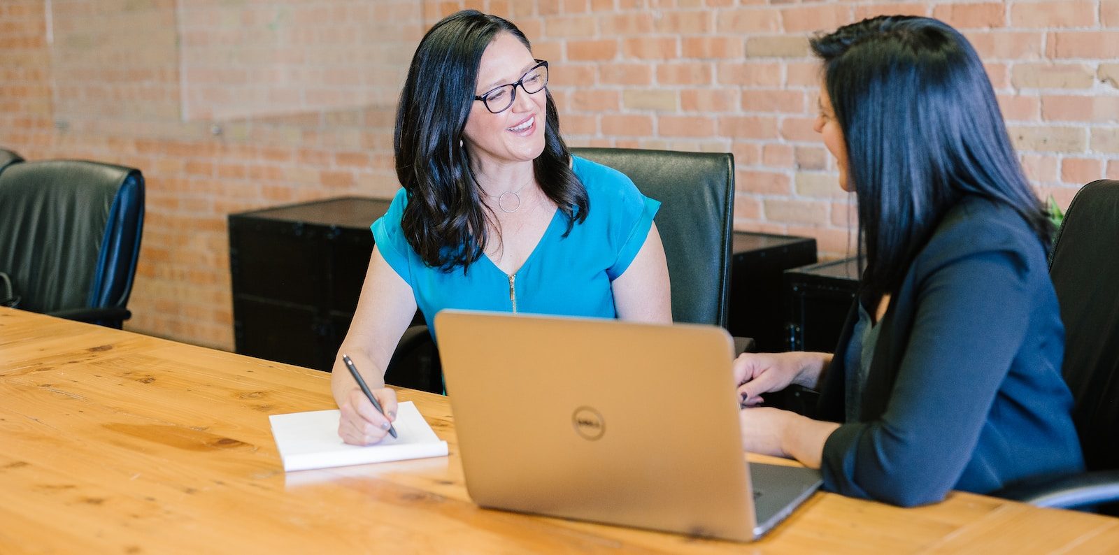 woman in teal t-shirt sitting beside woman in suit jacket